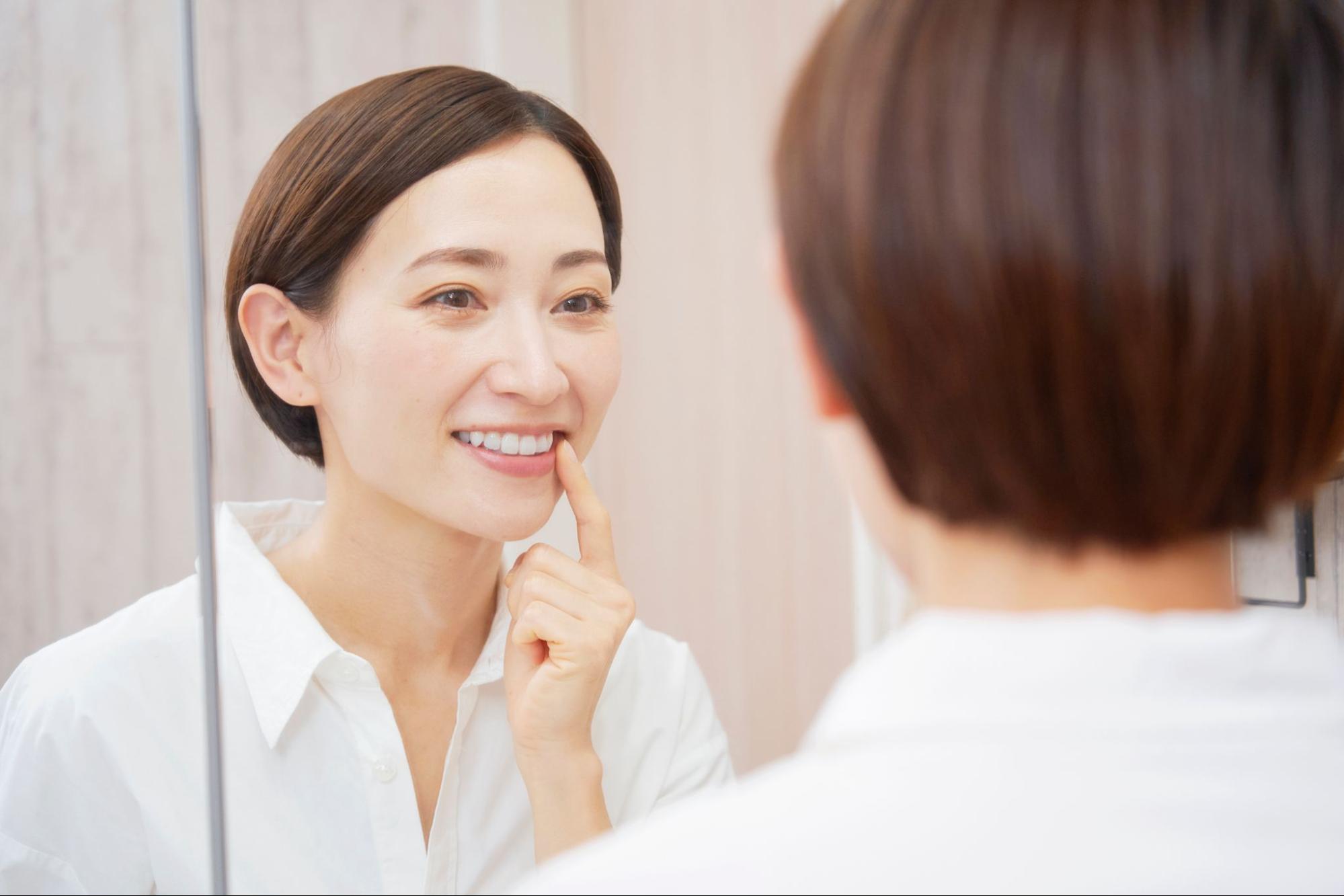 鏡で歯並びをチェックする笑顔の女性