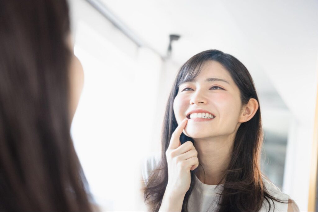 鏡で歯並びをチェックする笑顔の女性