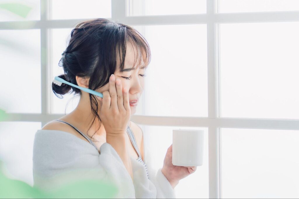歯痛でつらそうな歯磨き中の女性
