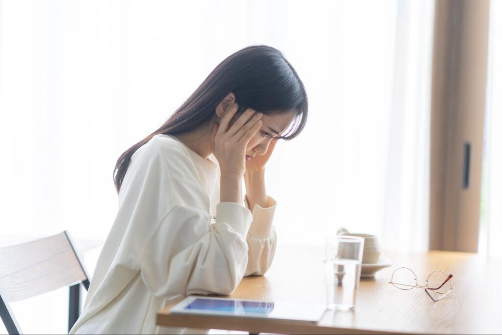 こめかみを押さえている女性