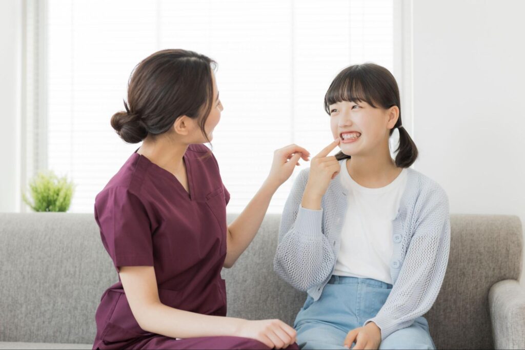 女の子の歯並びをチェックする医療従事者の女性
