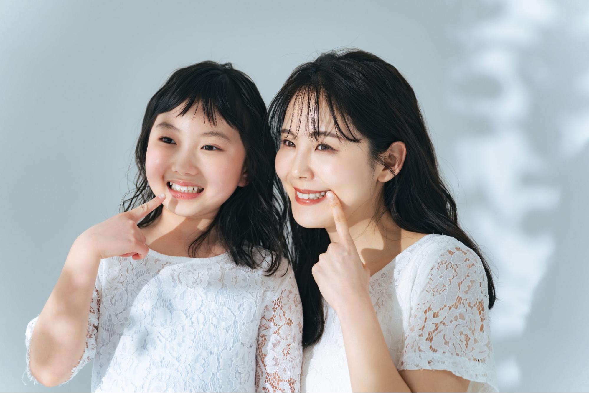笑顔で歯を見せる母と娘