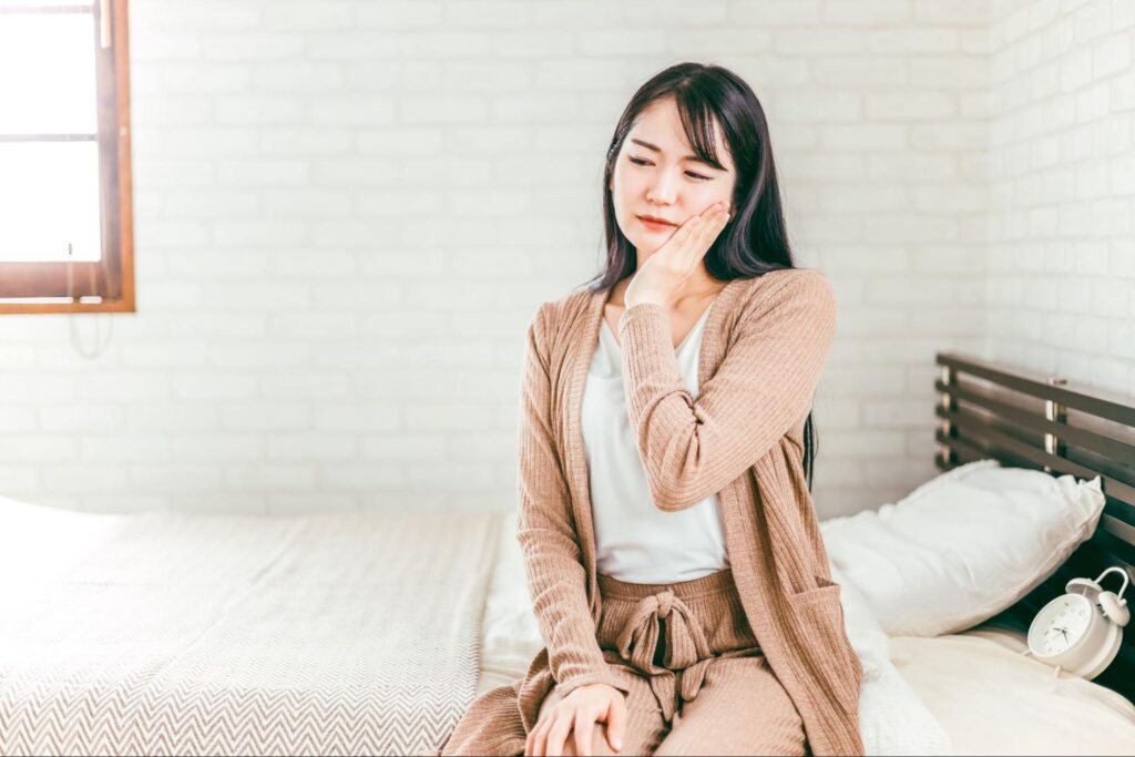 歯が痛くて頬を押さえる女性
