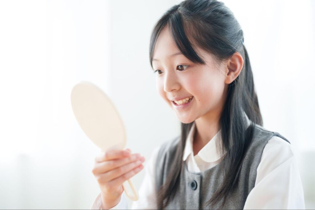 鏡で歯並びをチェックする女の子