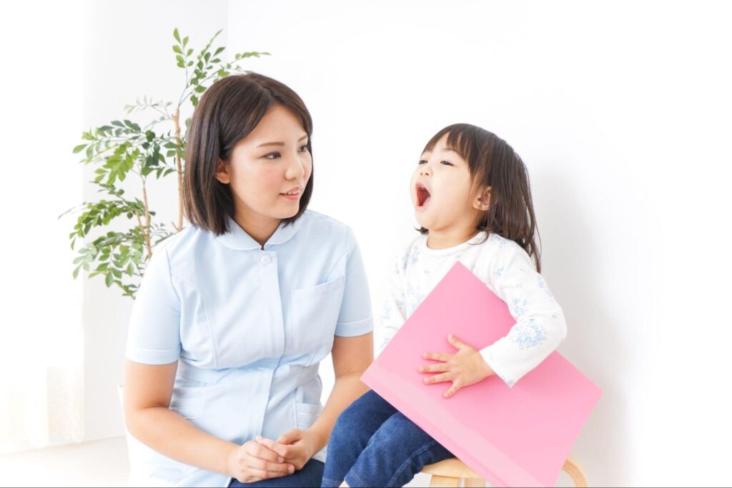 口を開ける女の子と口腔内チェックする医療従事者の女性