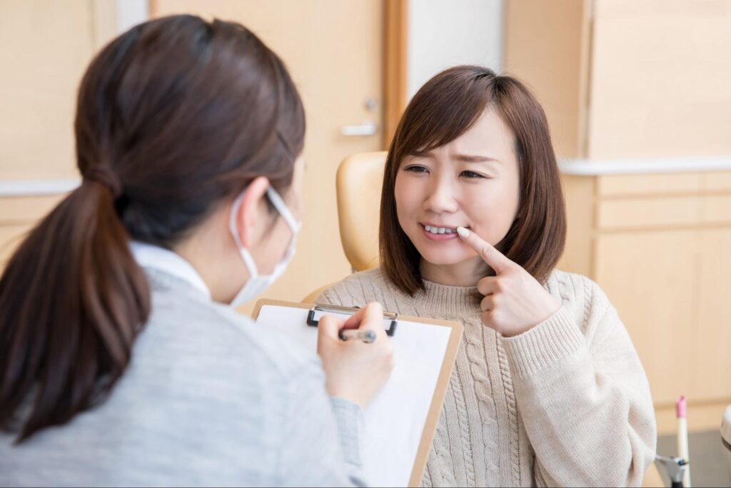 悪い歯並びについて歯科医療従事者に相談している女性