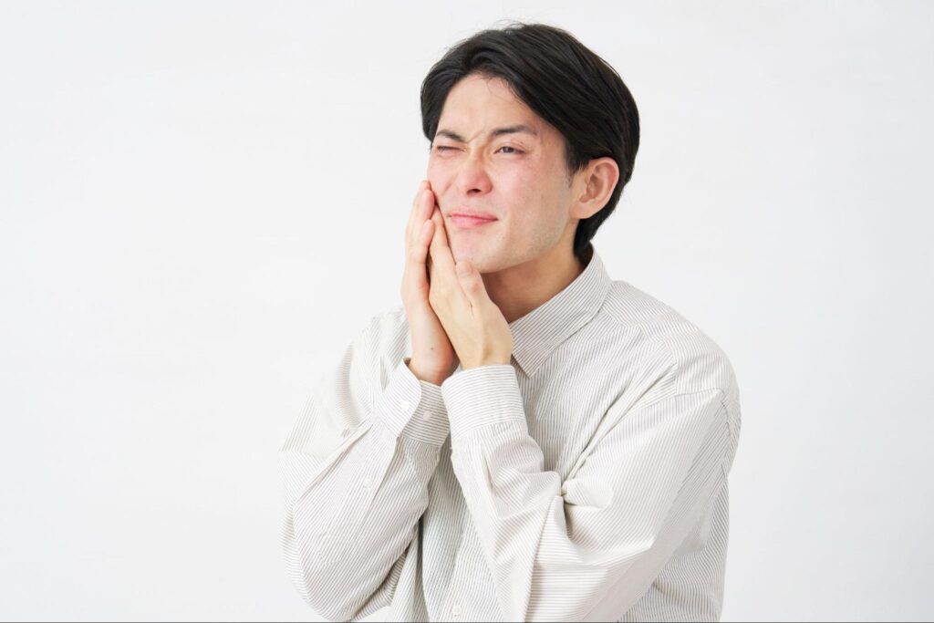 歯が痛くて頬を押さえる男性