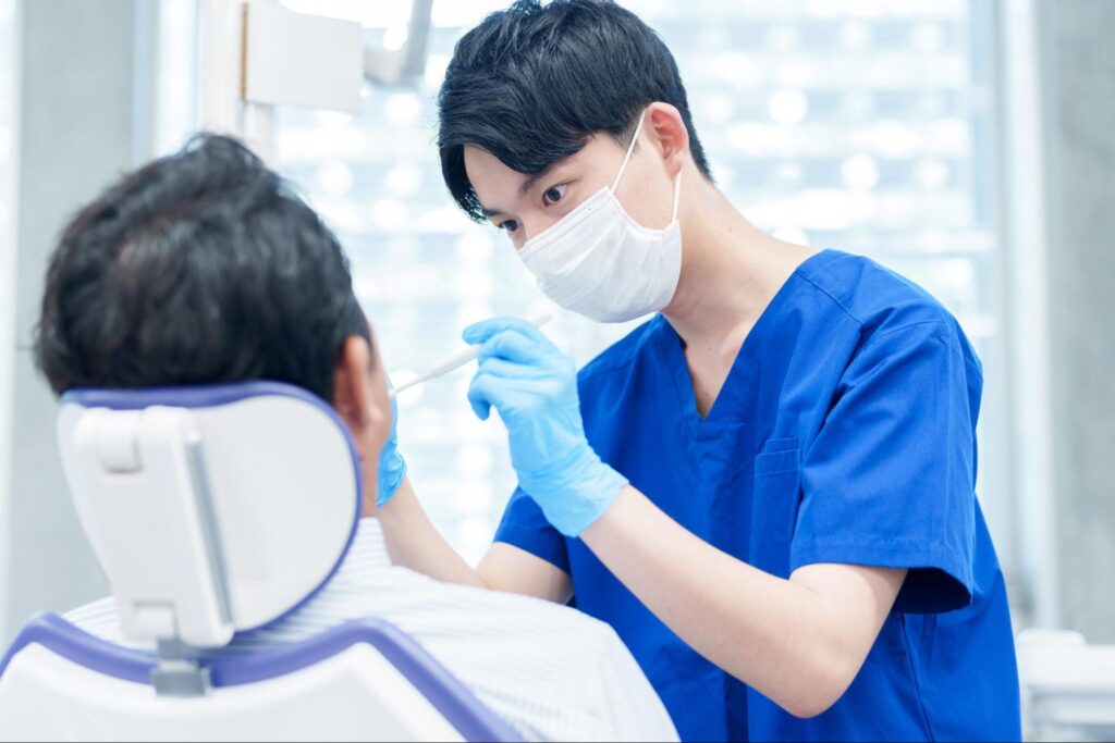 患者の口腔内をチェックしている男性歯科医師