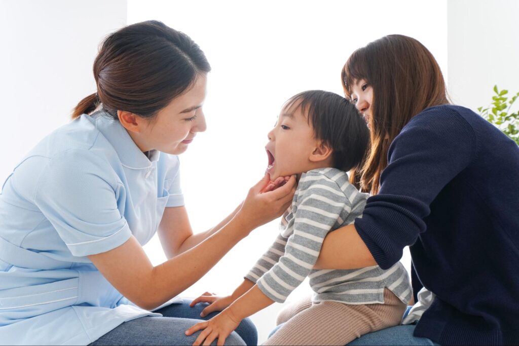 お母さんに抱っこされながら歯科検診を受ける子ども