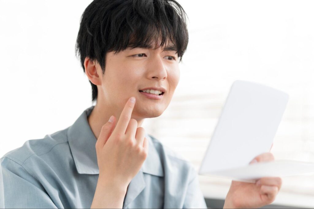 鏡で歯並びをチェックする浮かない顔の男性