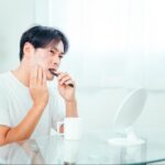 歯磨き中に歯の痛みを感じる男性