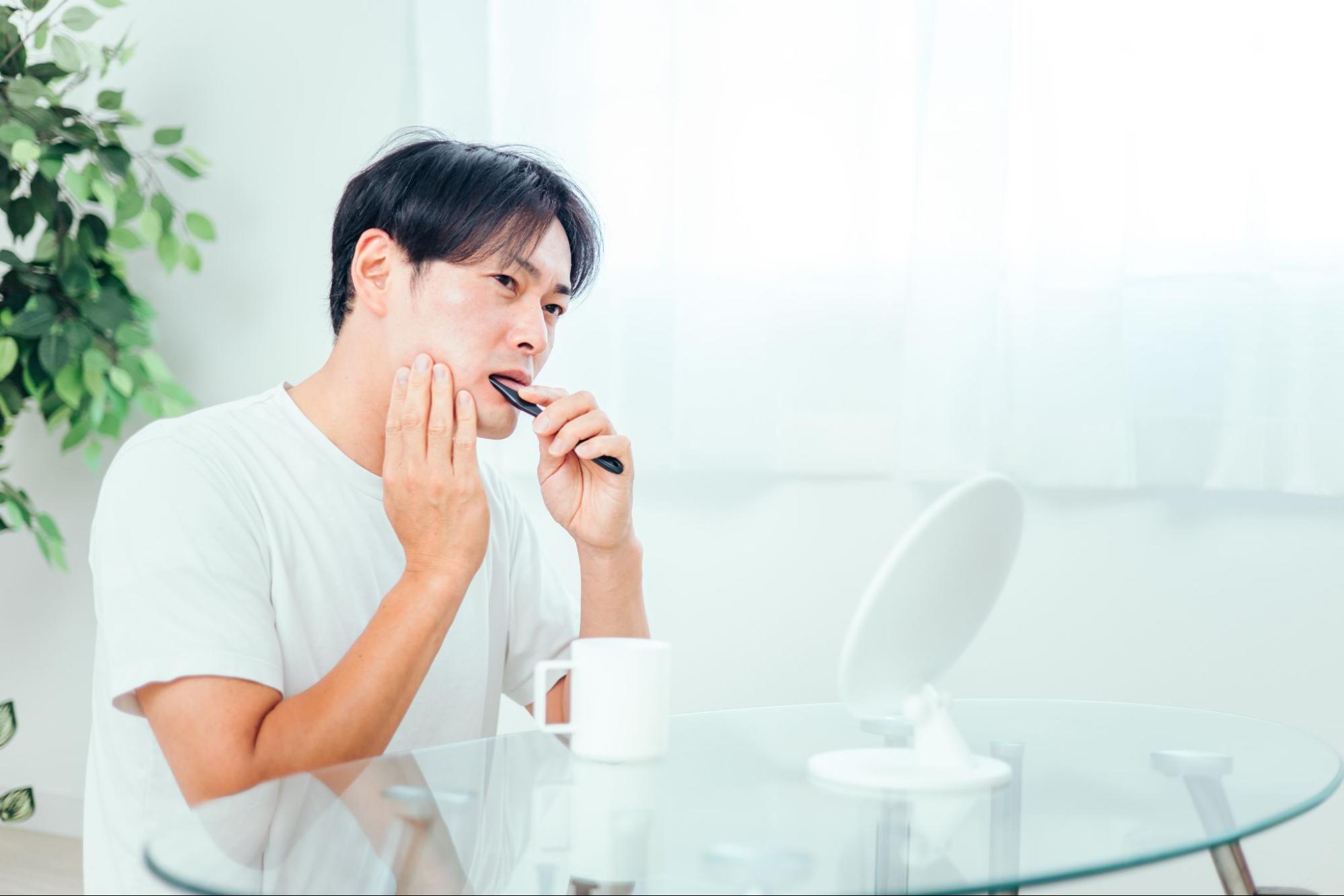 歯磨き中に歯の痛みを感じる男性