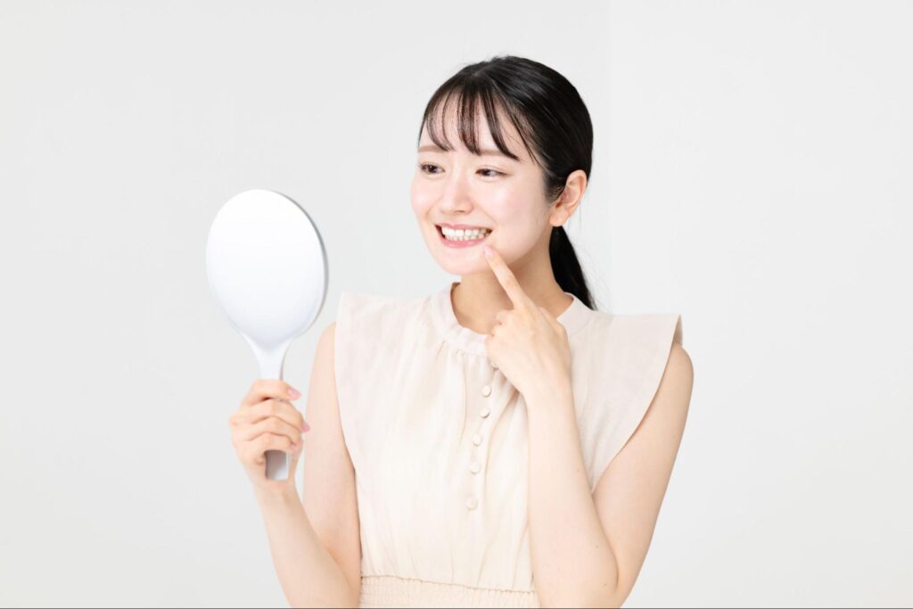 鏡で歯並びをチェックする笑顔の女性