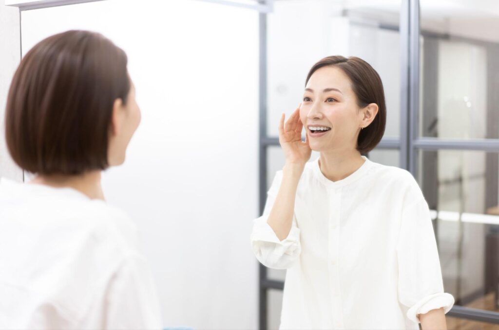 鏡で歯並びをチェックする笑顔の女性