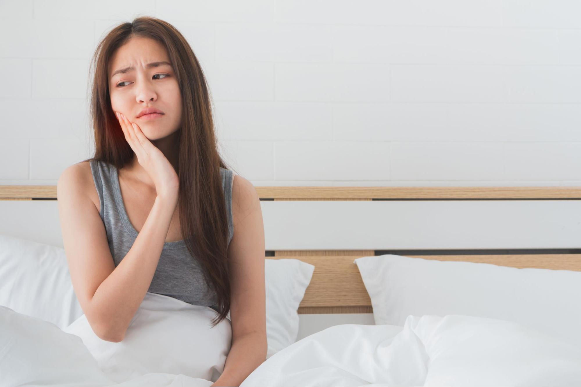 歯が痛そうにしている寝起きの女性