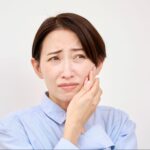 歯が痛くて頬を押さえる女性