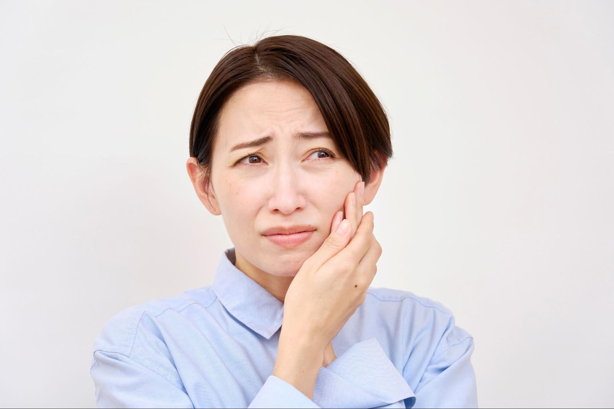 歯が痛くて頬を押さえる女性