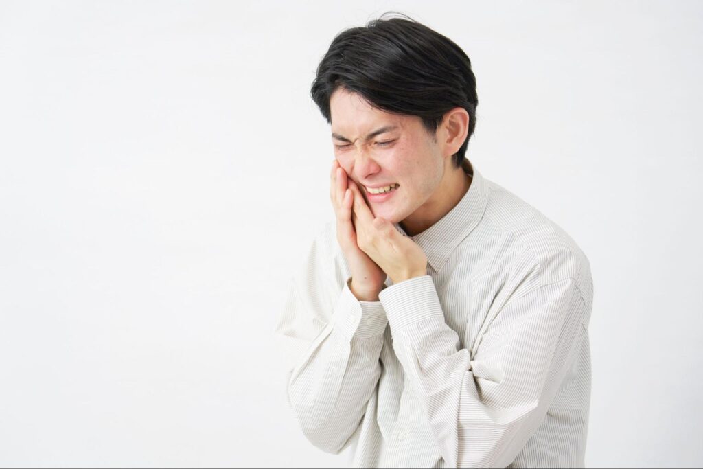 歯が痛くて頬を押さえる男性