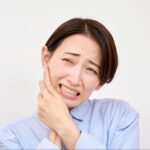 歯が痛くて頬を押さえる女性