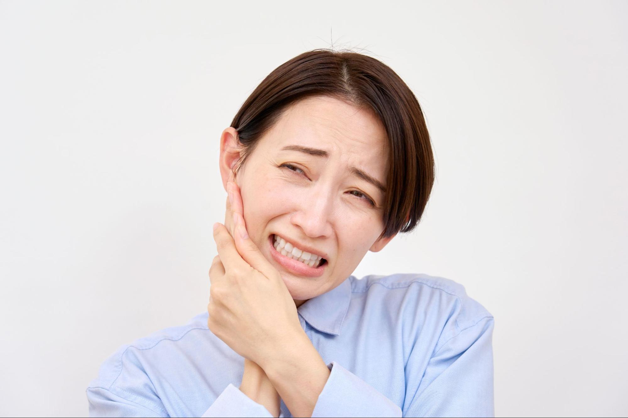 歯が痛くて頬を押さえる女性